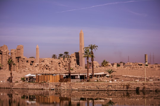 brown concrete building near body of water during daytime in Karnak Egypt