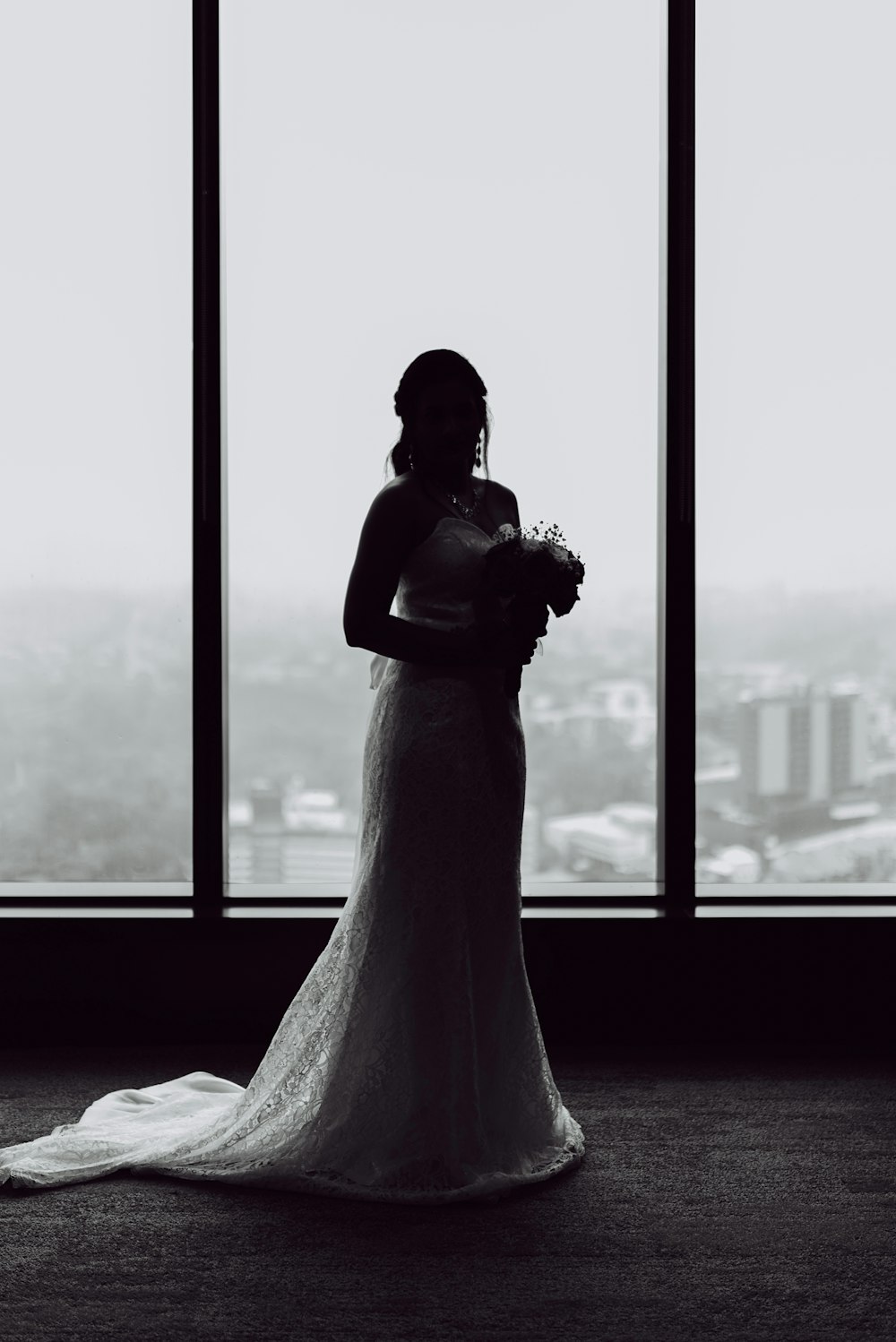 woman in white wedding gown standing near window