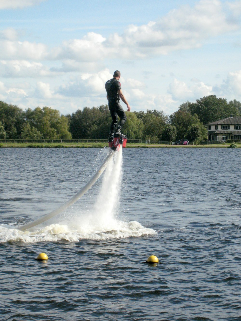 man in black shirt and black pants playing with yellow ball on water during daytime