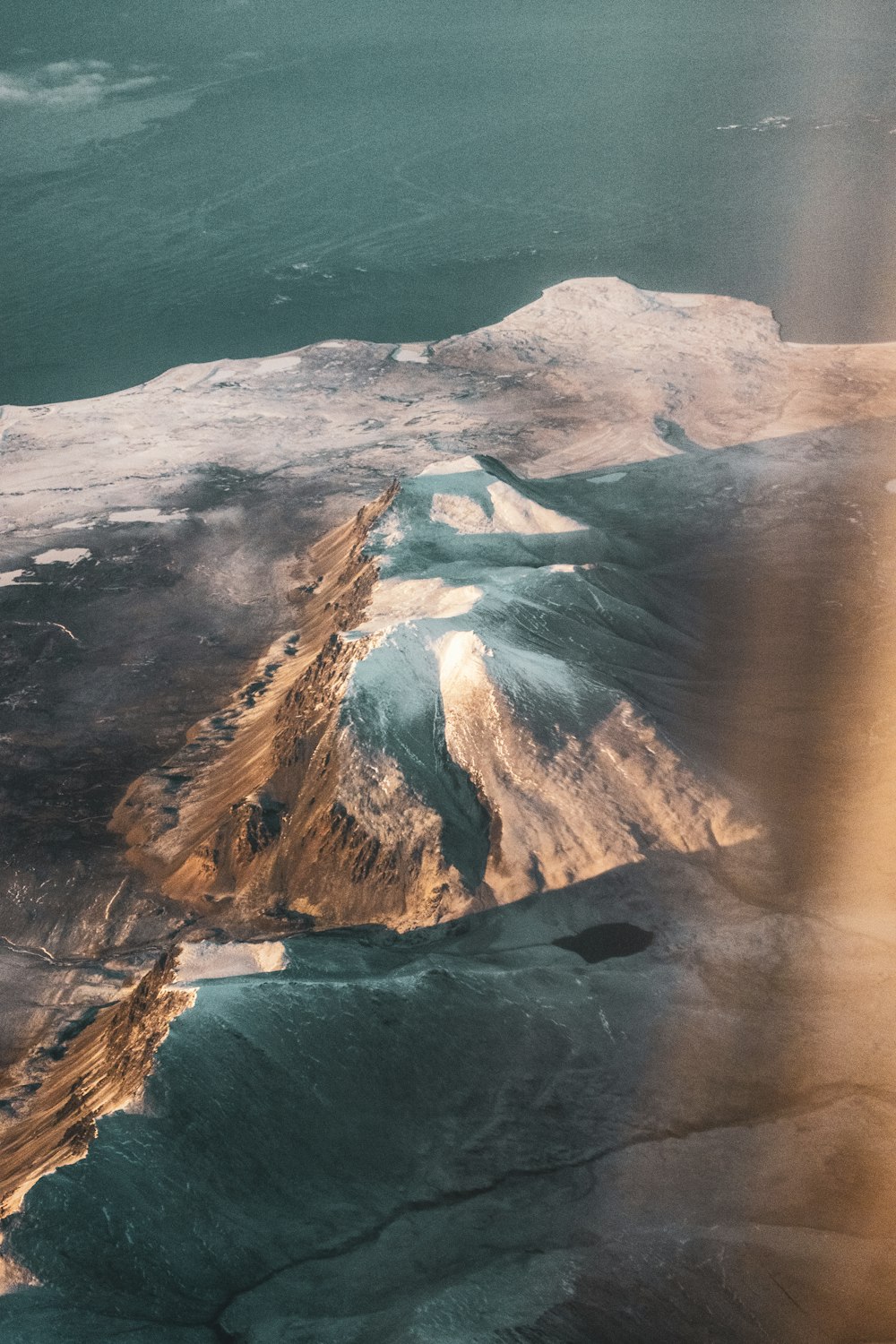 brown and white mountain beside body of water during daytime