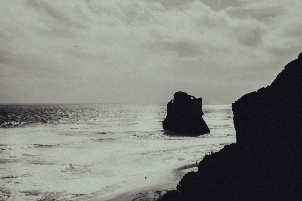 grayscale photo of rock formation on beach