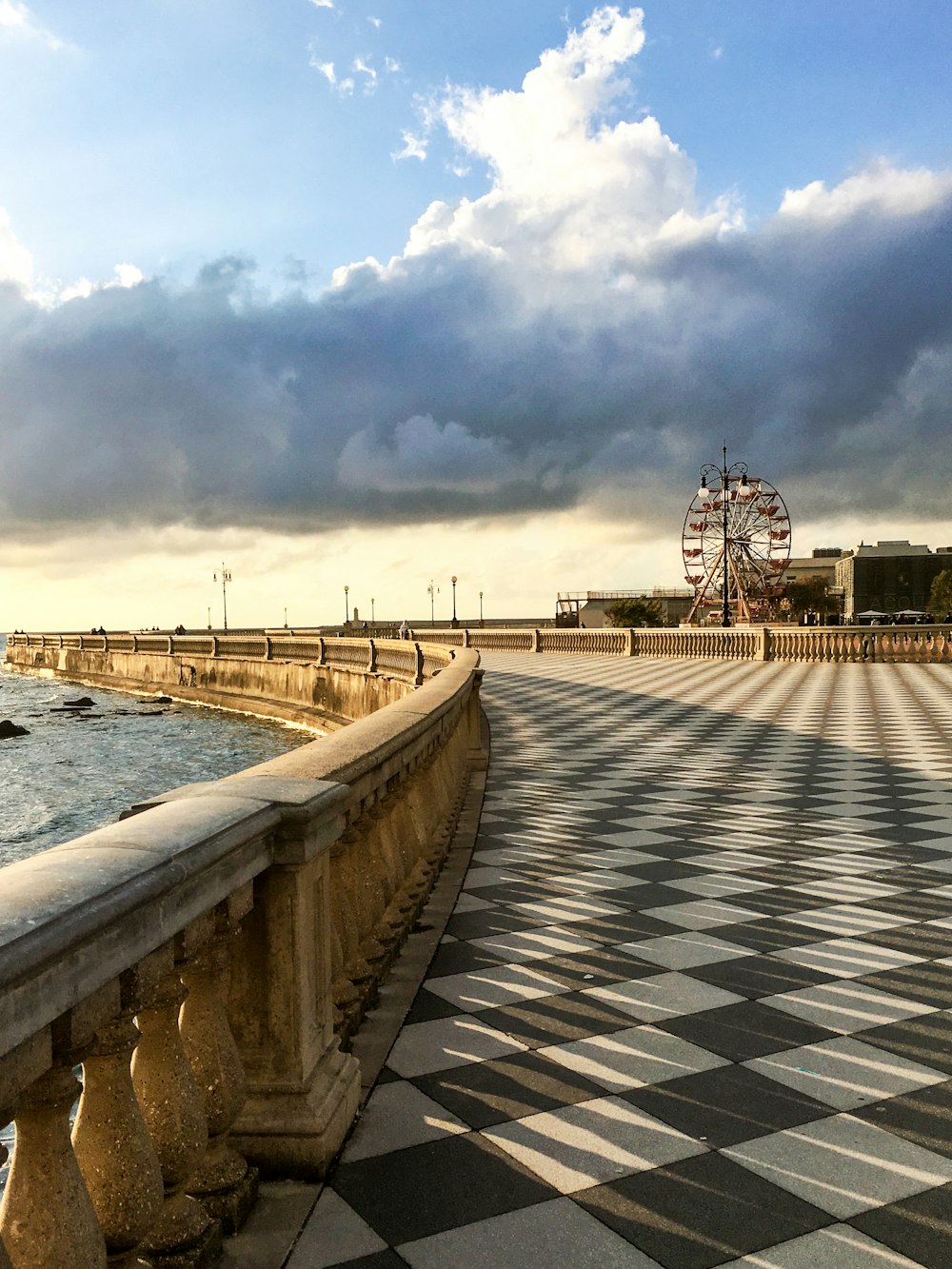 gray concrete bridge over body of water under cloudy sky during daytime