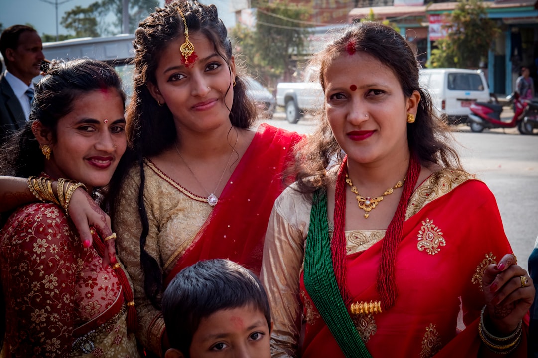 woman in red and green sari beside girl in green and brown dress