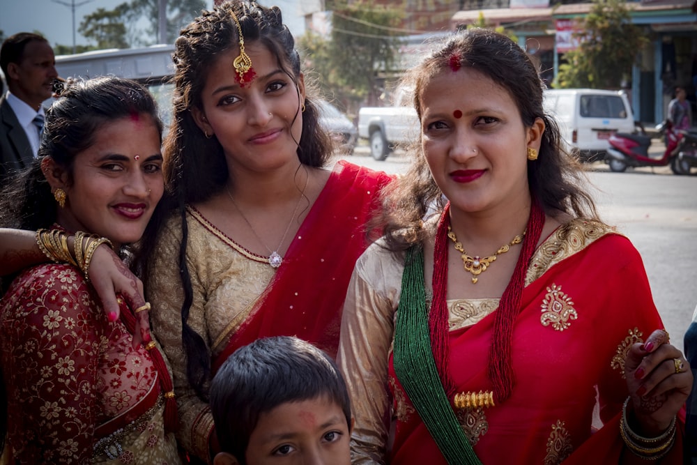 Femme en sari rouge et vert à côté d’une fille en robe verte et marron