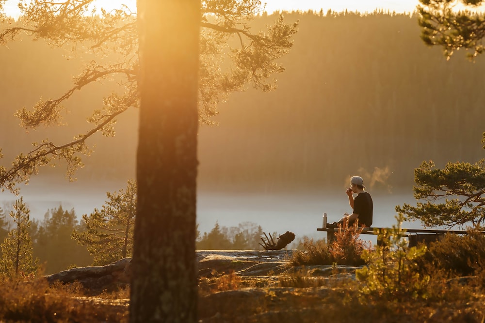 man sitting on bench near body of water during daytime