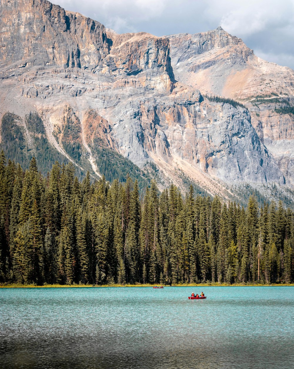 person riding on boat on lake near mountain during daytime