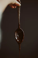 Hands holding a tasting spoon with melted chocolate during a cozy chocolate tasting experience.