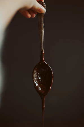 Hands holding a tasting spoon with melted chocolate during a cozy chocolate tasting experience.
