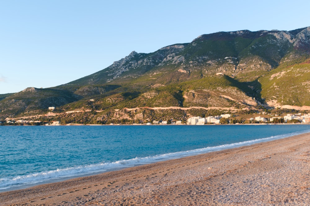 green and brown mountain beside blue sea under blue sky during daytime