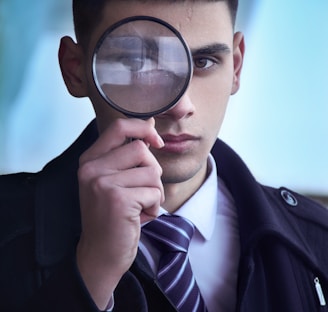 man in black suit holding magnifying glass