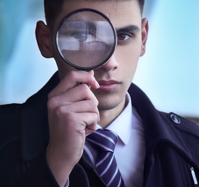 man in black suit holding magnifying glass