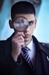 man in black suit holding magnifying glass