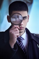 man in black suit holding magnifying glass
