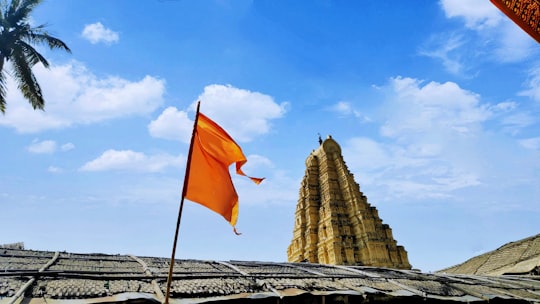 orange and white flag on pole during daytime in Hampi India