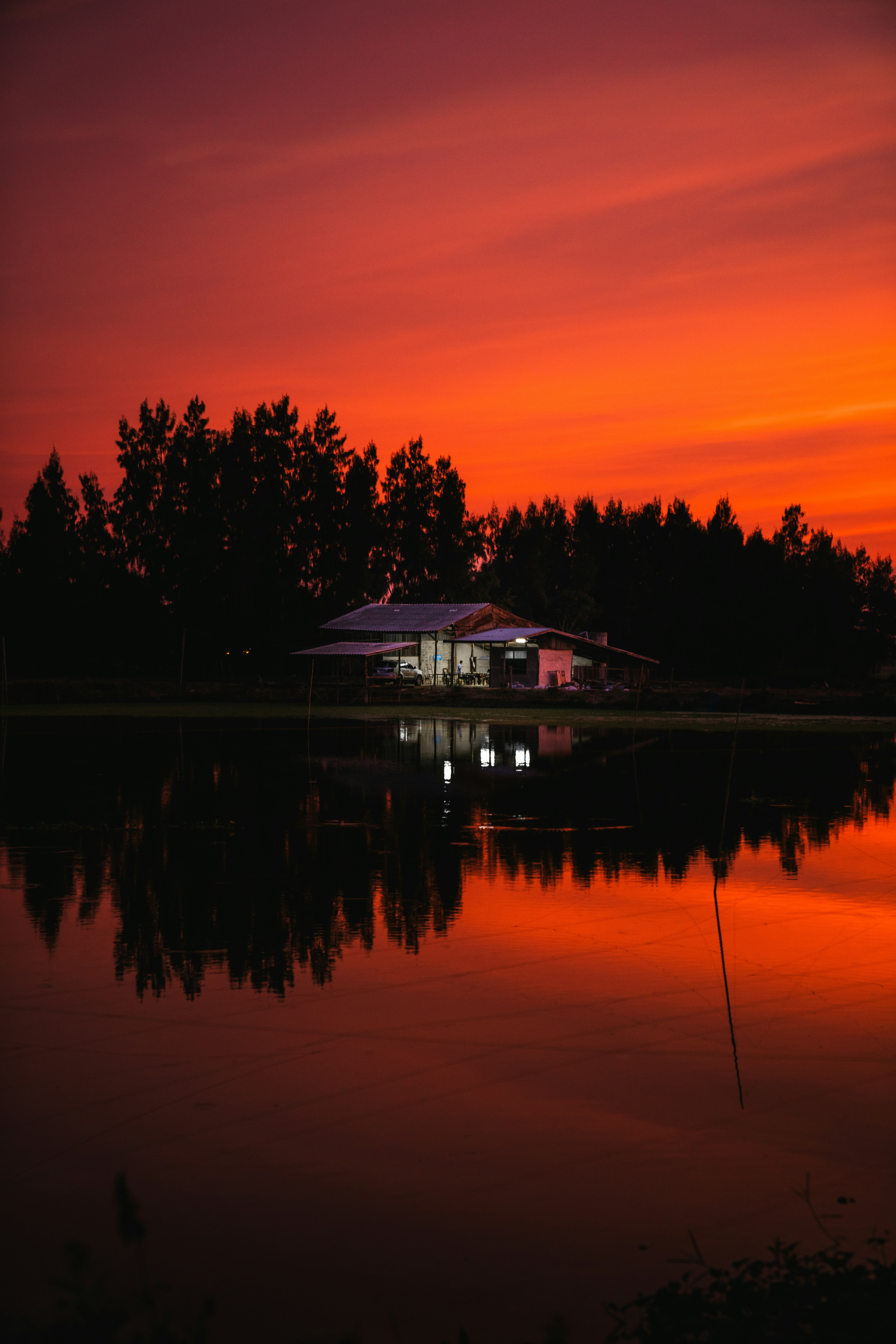 silhouette of house near body of water during sunset