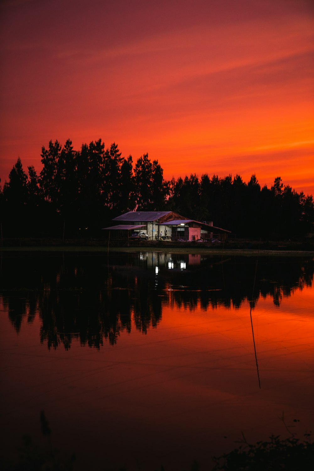 silhouette of house near body of water during sunset