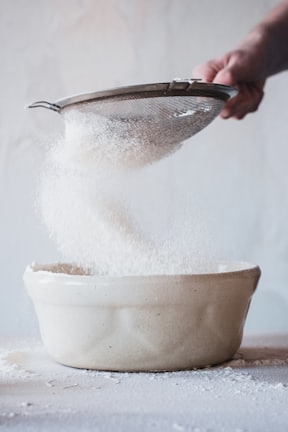 person pouring water on white ceramic bowl