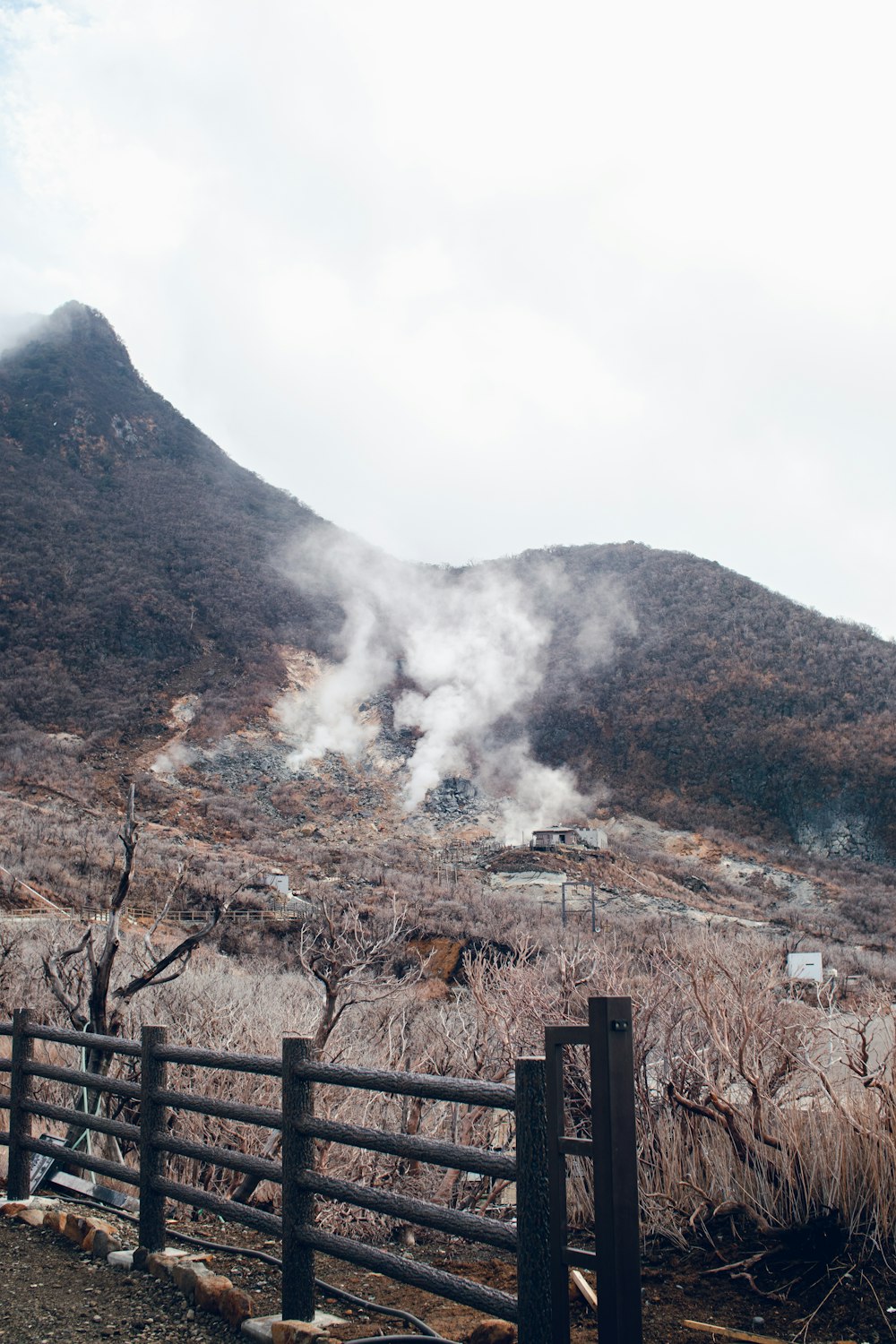 brown wooden fence on brown mountain under white clouds during daytime