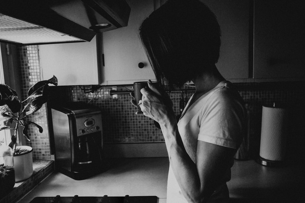 man in white t-shirt holding black smartphone