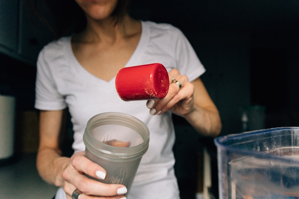 woman in white crew neck t-shirt holding red plastic cup