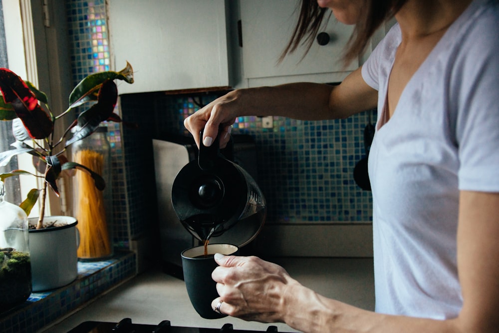 woman in white t-shirt holding black ceramic mug