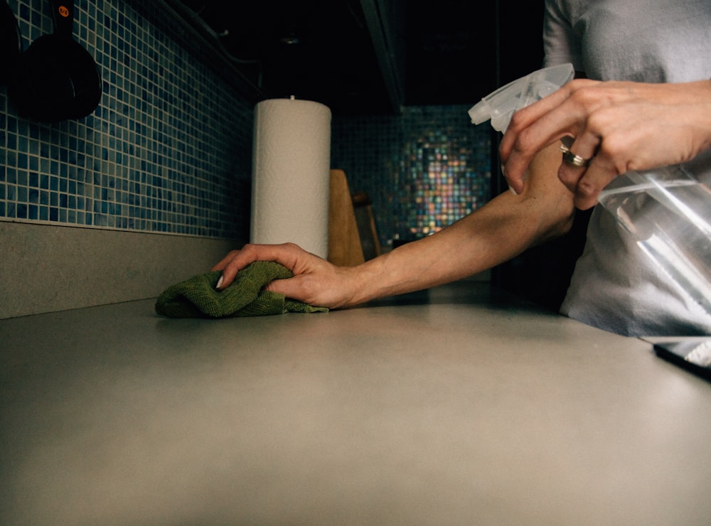 person holding white paper near white paper towel roll