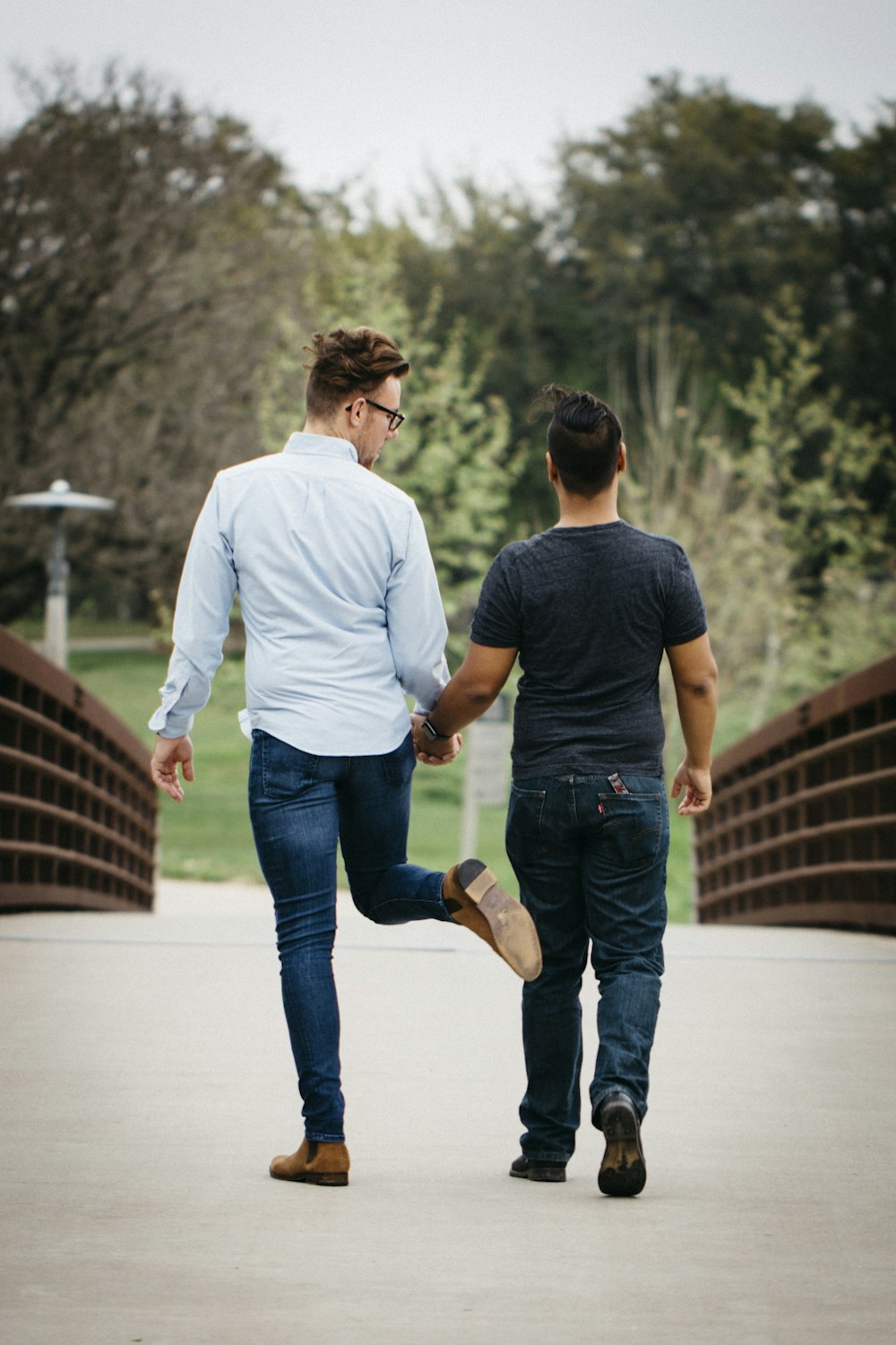man in white long sleeve shirt and blue denim jeans holding hands with woman in blue