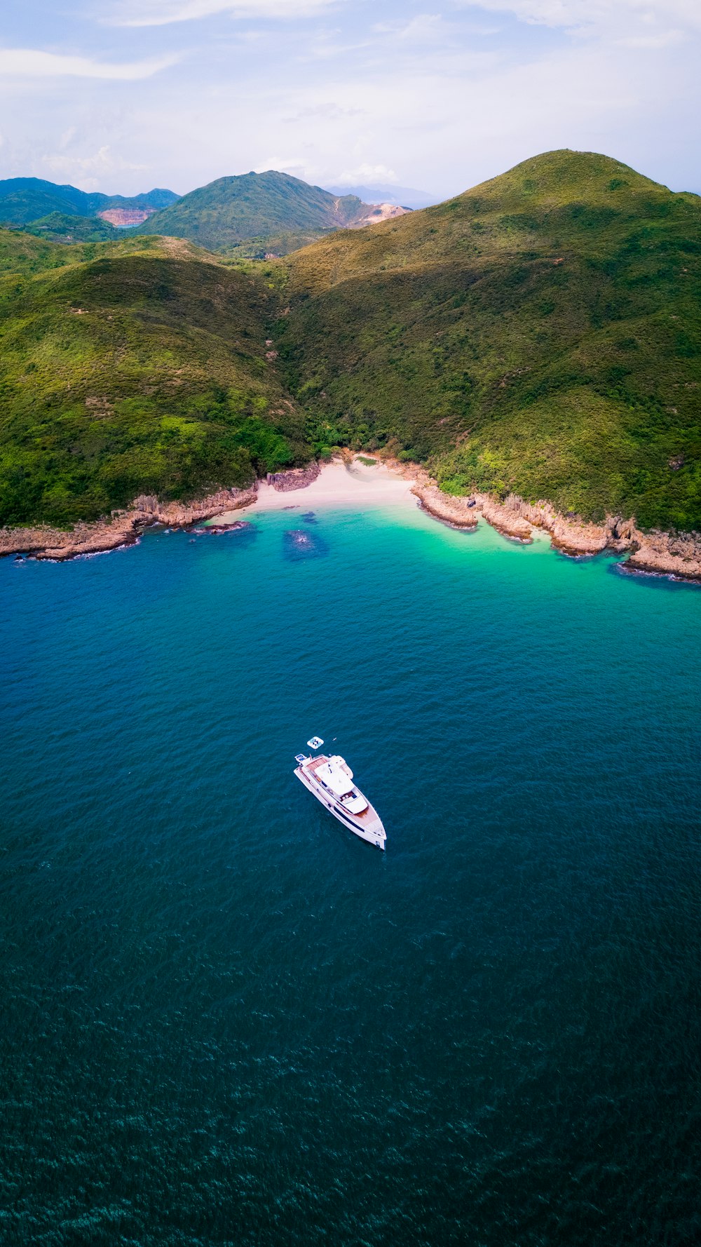 white boat on sea near green mountain during daytime