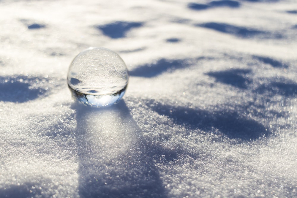 sfera di vetro trasparente su neve bianca