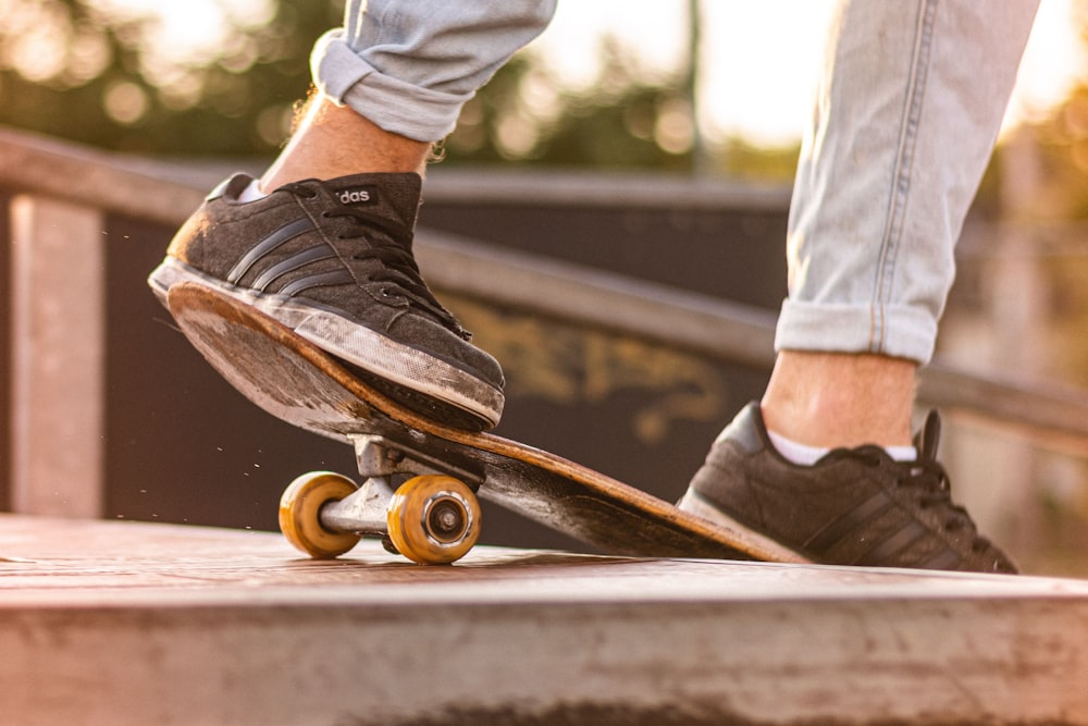 person in blue denim jeans and brown shoes sitting on brown wooden bench