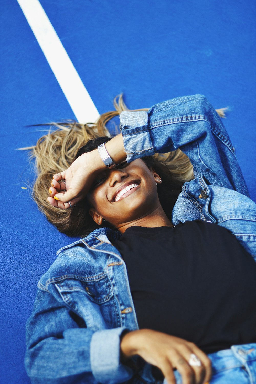 woman in black shirt and blue denim jacket smiling