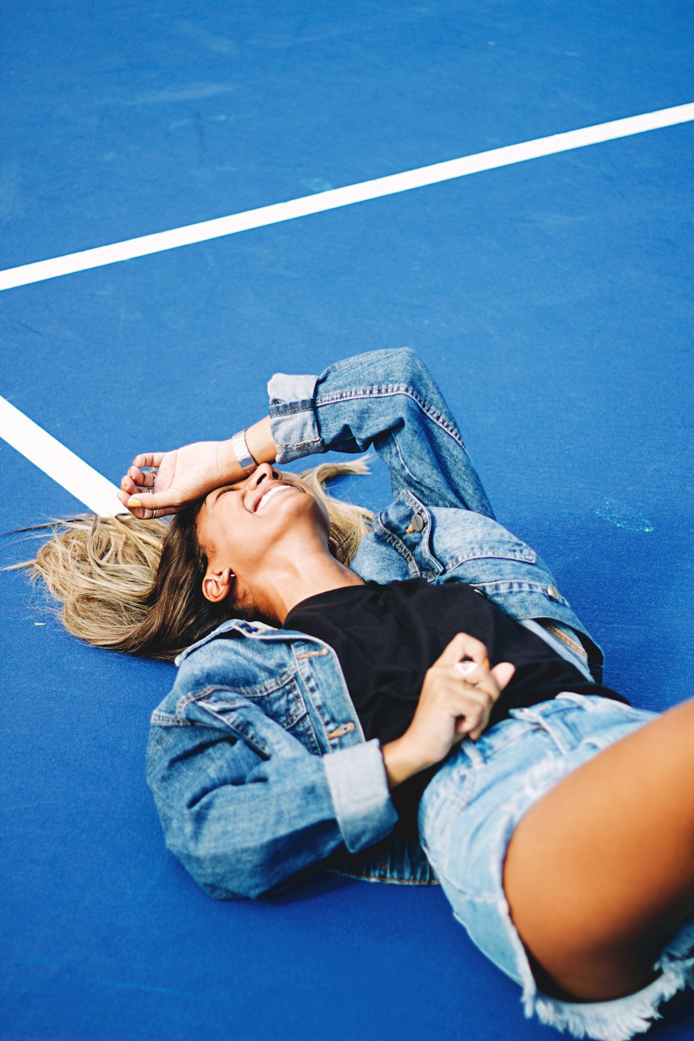 woman in black shirt lying on blue textile