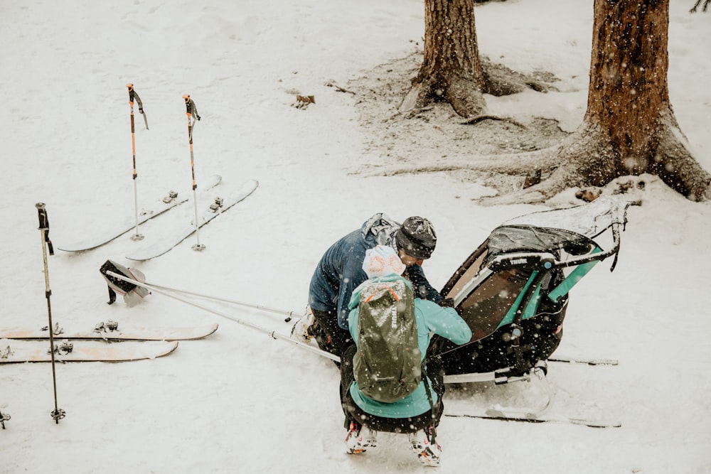 man in blue jacket riding green and black snow sled