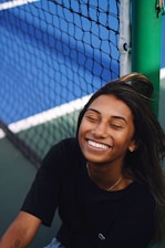 A joyful child holding a donated tennis racket on a sunny court, ready to play.