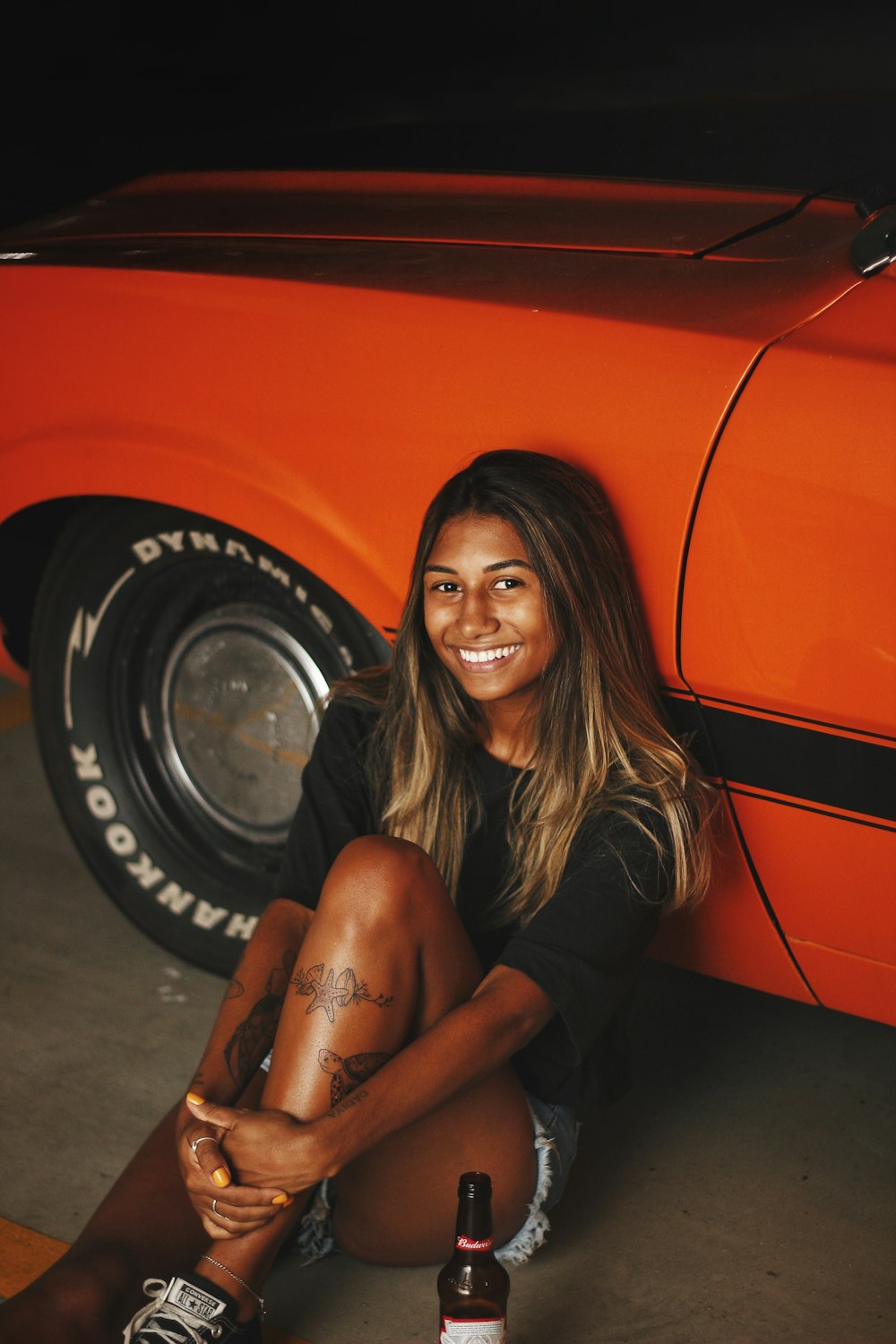 woman in black long sleeve shirt sitting on orange car