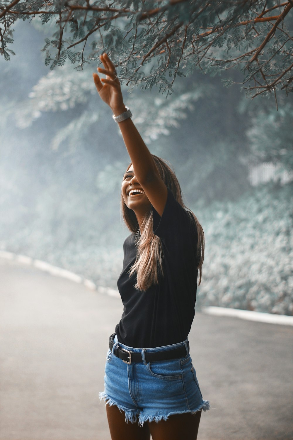 woman in black long sleeve shirt and blue denim jeans standing on road during daytime