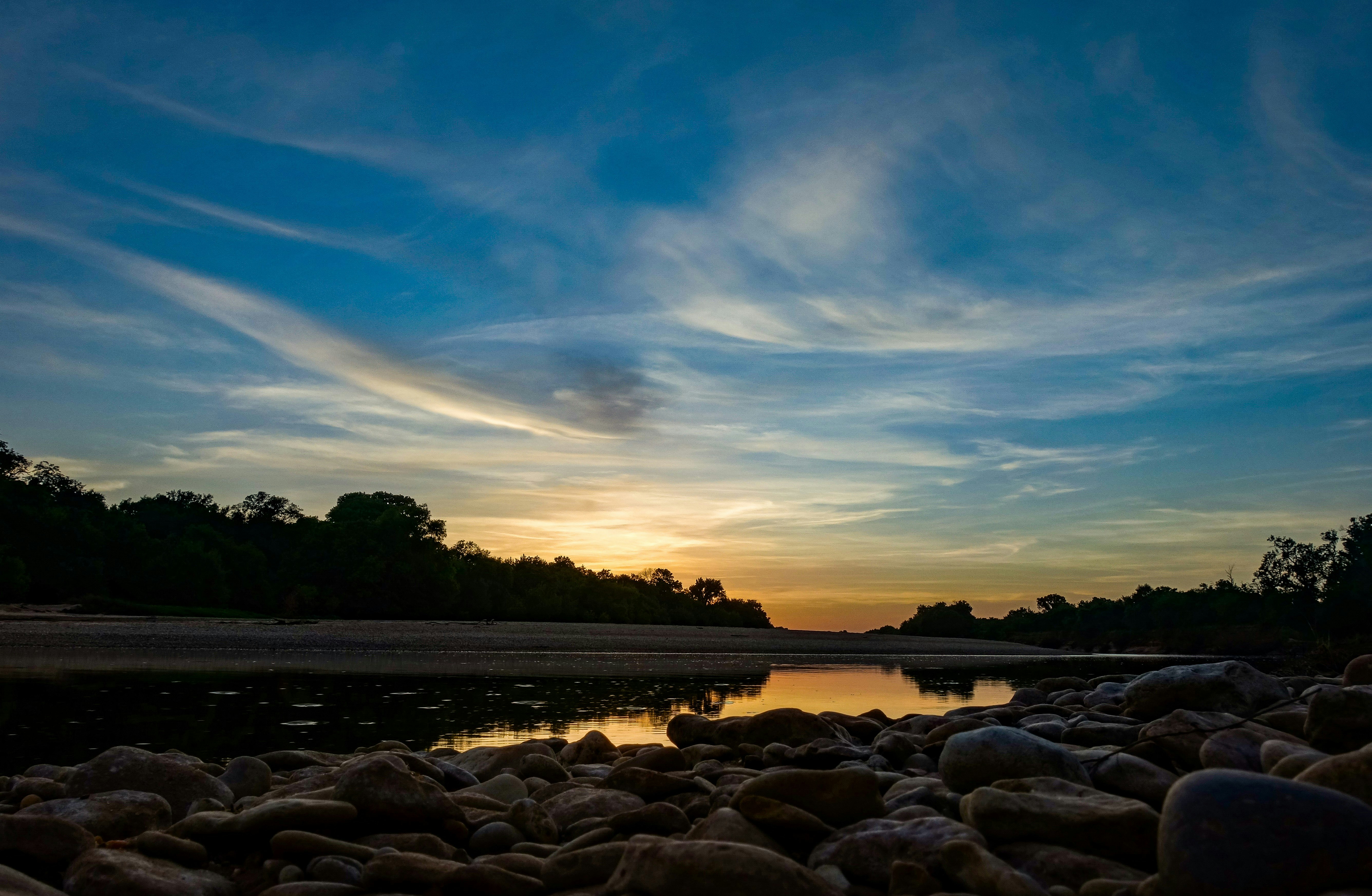 gray rocks near body of water during sunset