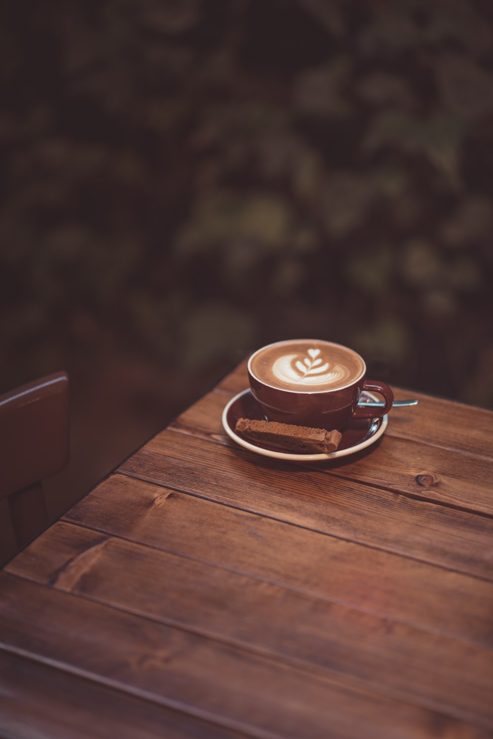 cappuccino in brown ceramic cup on brown wooden table