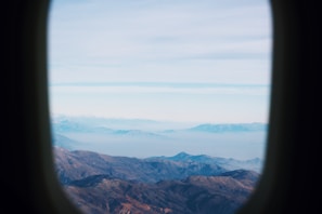Aerial view of a plane flying over a mountain range with clear skies