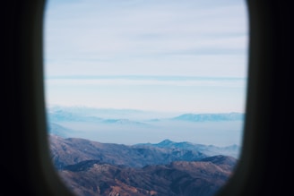 Aerial view of a plane flying over a mountain range with clear skies