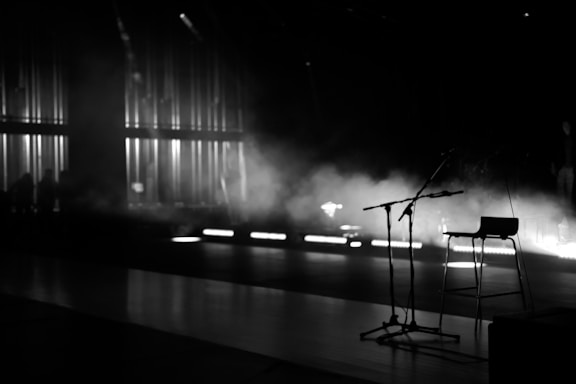 A dimly lit elegant backstage corner with red velvet curtains and a vintage microphone stand.