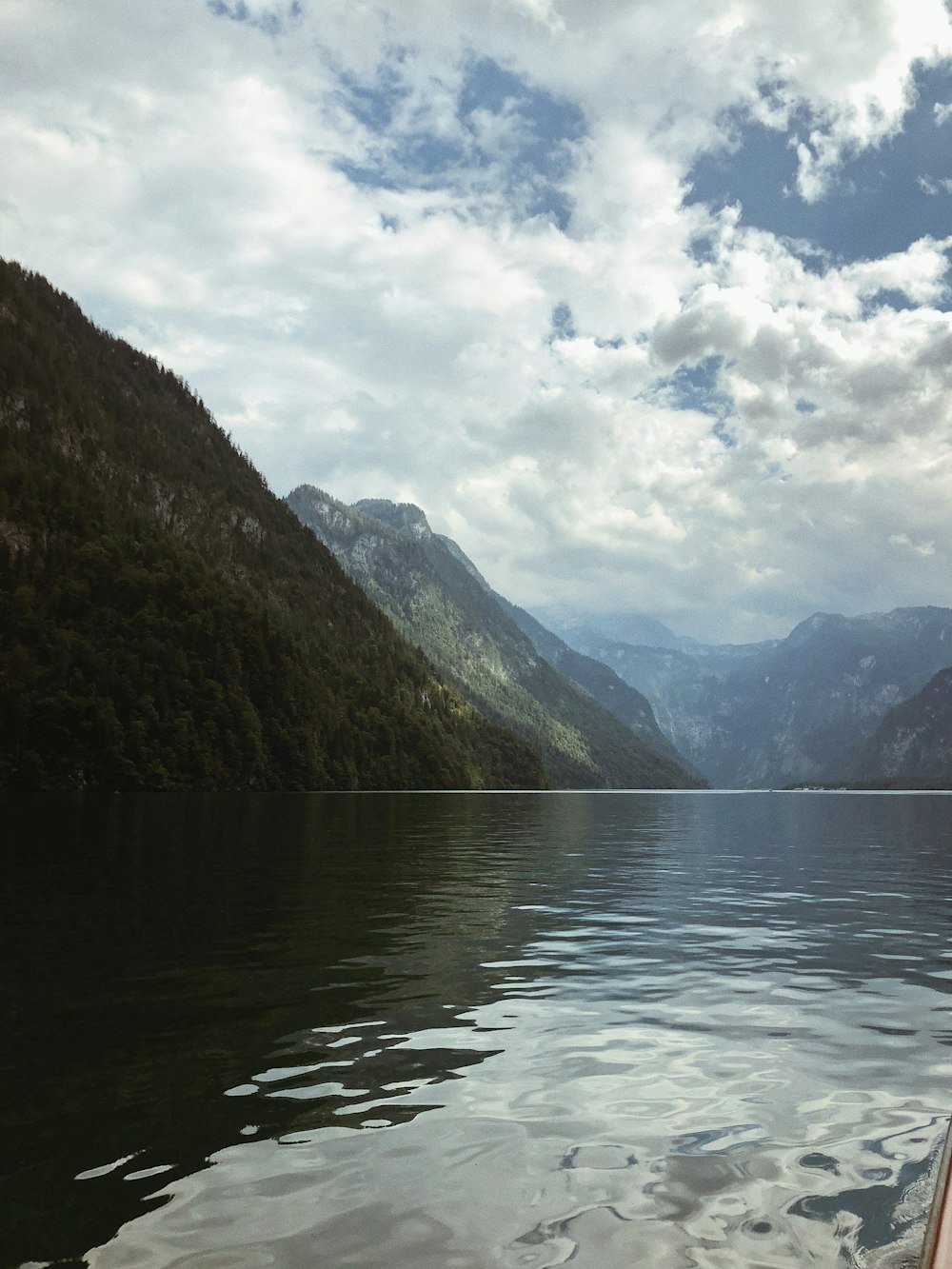 green mountains beside body of water under cloudy sky during daytime