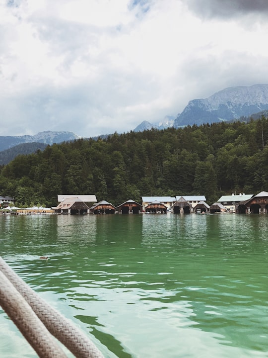 brown wooden houses on green lake near green mountain during daytime in Berchtesgaden National Park Germany