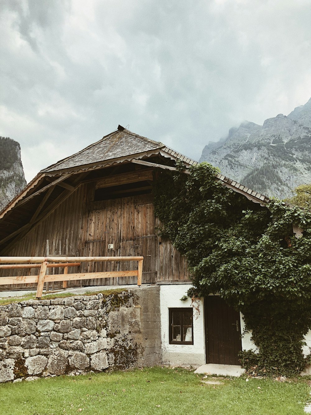 brown wooden house near green trees and mountain during daytime