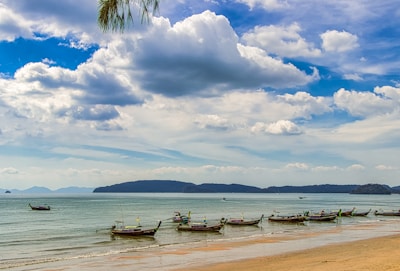 A serene ocean scene with traditional Omani boats floating near a rocky coastline.