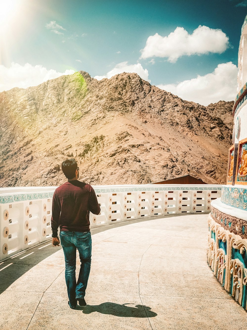 man in black jacket and blue denim jeans standing on white concrete bridge during daytime