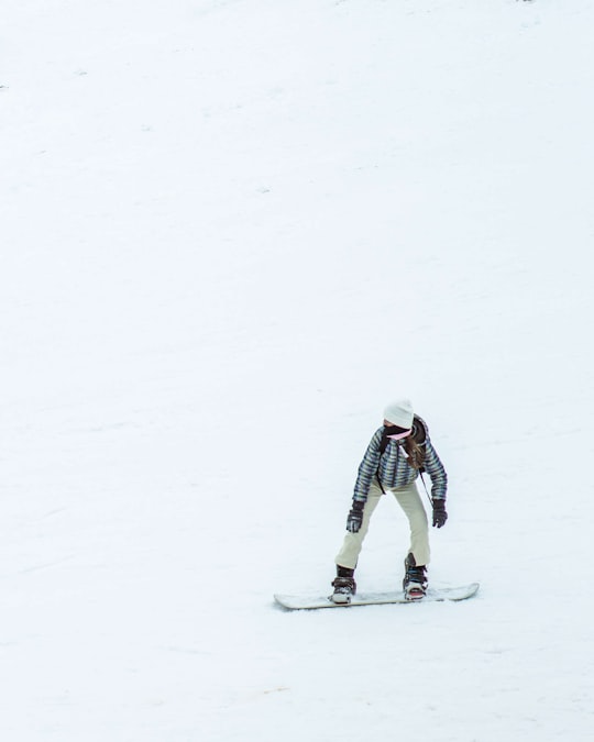 person in white jacket and black pants riding snow ski in Kalavryta Greece