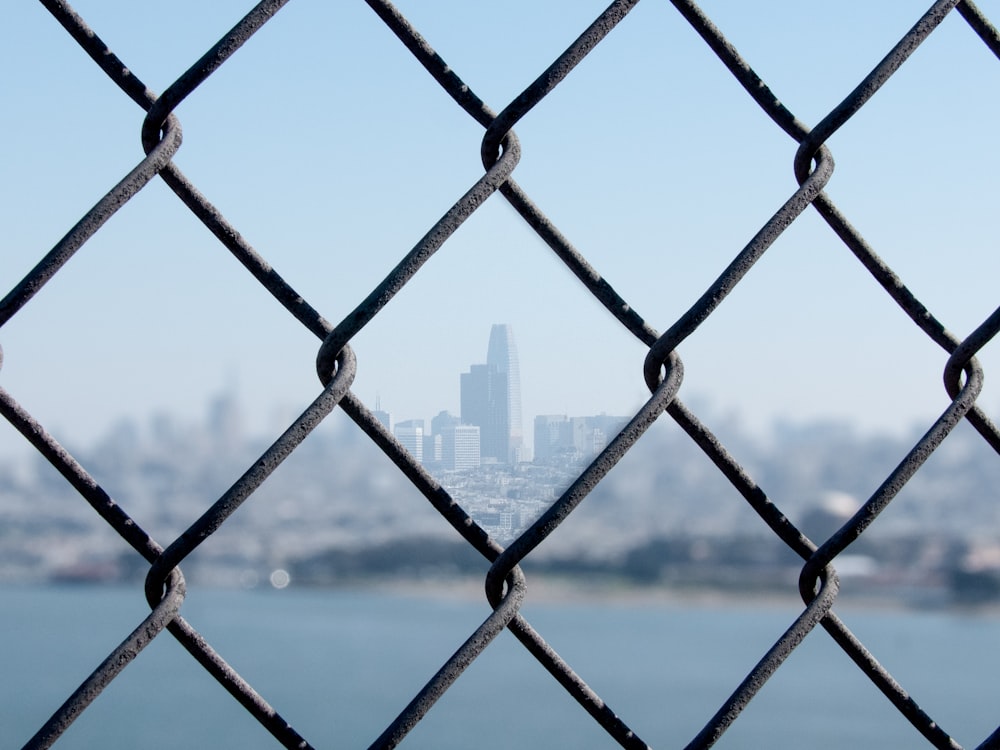 gray chain link fence across city buildings during daytime