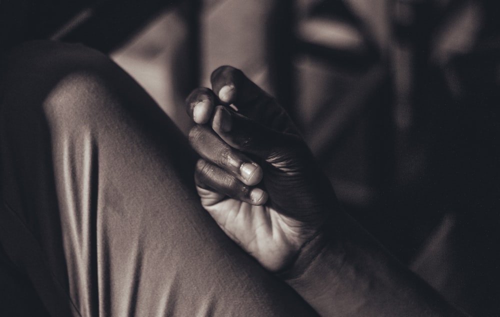Foto en escala de grises de una persona sosteniendo la mano del bebé