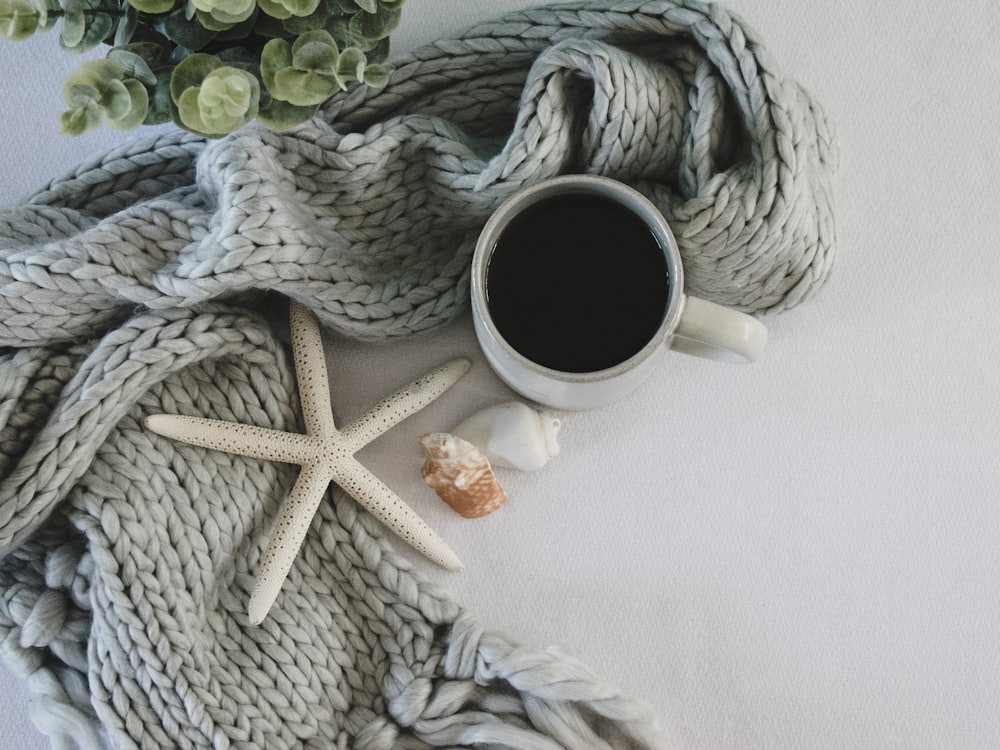 white ceramic mug on white and black knit textile